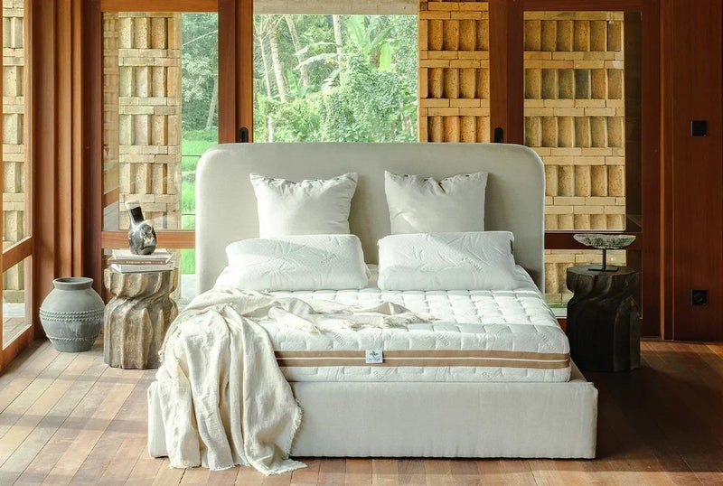 Bedroom with a natural wood bed frame and Heveya latex mattress, styled with slatted wood shutters and soft natural light
